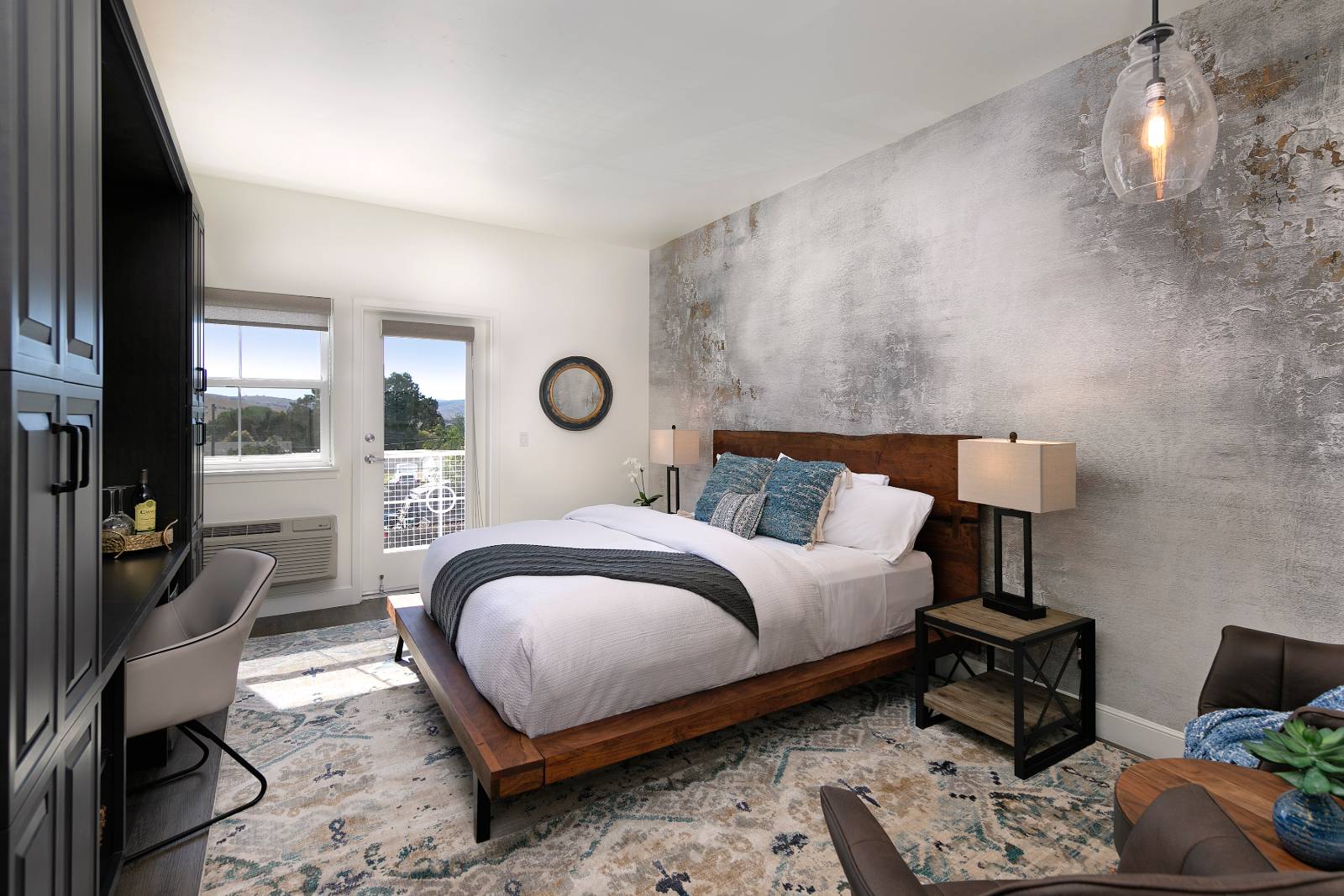 Deluxe King room with a wooden bed, a textured feature wall and French doors